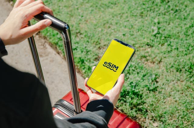 Travelers with luggage holding smartphone with esim